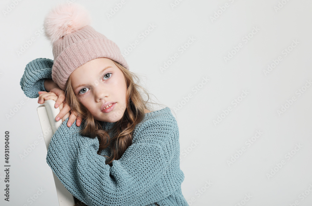 Happy little girl wearing blue sweater and winter hat on white background Happy little girl wearing blue sweater and winter hat on white background