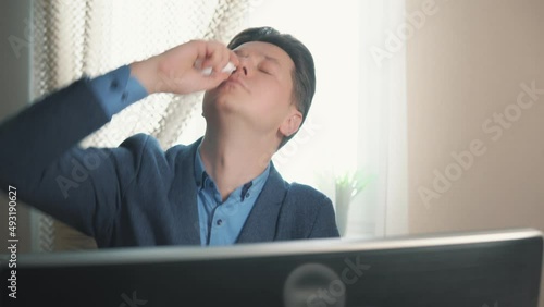 man using nasal medicine while working at computer