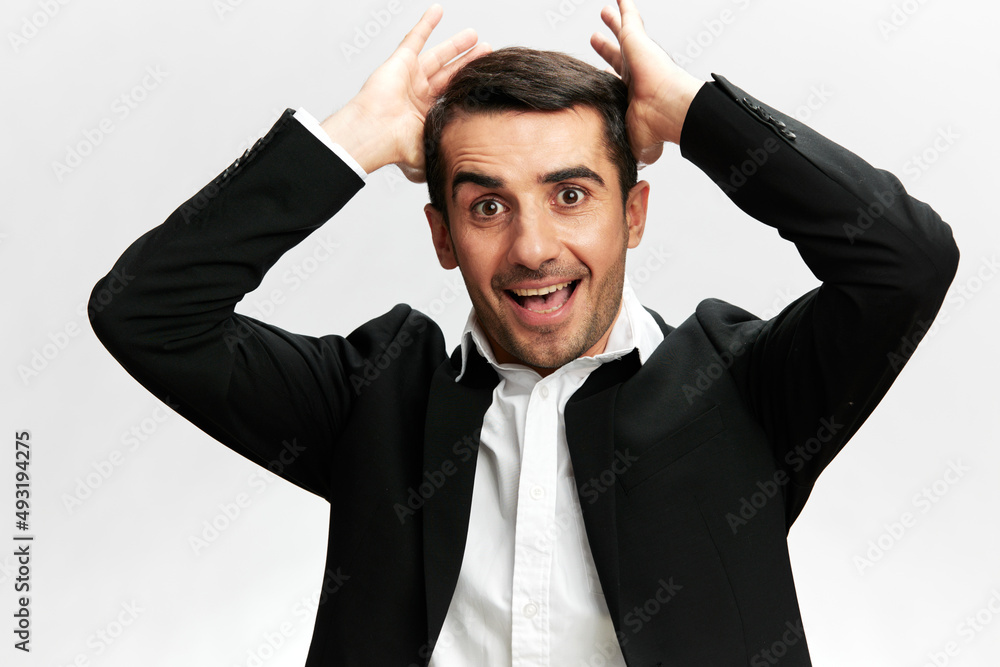 Cheerful business man in a black suit straightens his hair with his hands emotions professional. white studio background, copy space Cheerful business man in a black suit straightens his hair with his hands emotions professional. white studio background, copy space