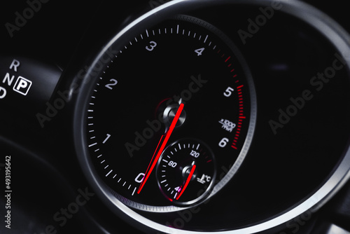 Car tachometer with glowing red indicators close-up view, of luxury dashboard in sport car