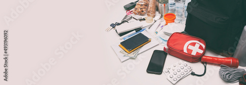 Emergency backpack equipment organized on the table. Documents, water,food, first aid kit and another items needed to survive.