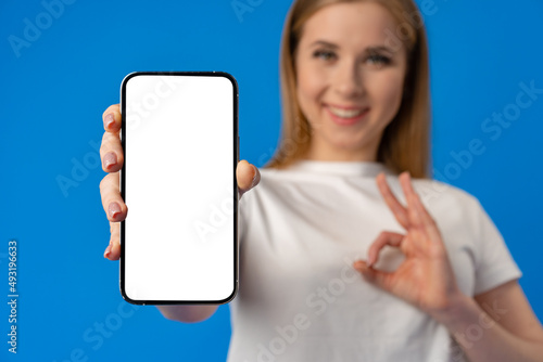 Young smiling woman showing blank screen smartphone in studio