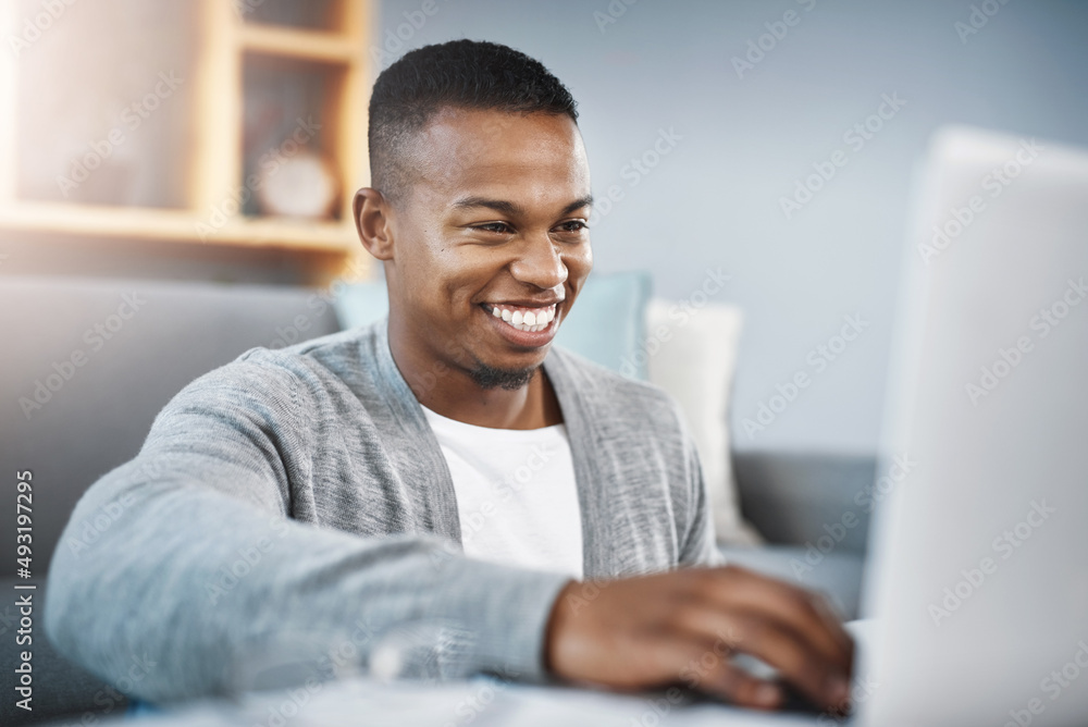 Connect to the world from the comfort of home. Shot of a happy young man using a laptop while relaxing at home. Connect to the world from the comfort of home. Shot of a happy young man using a laptop while relaxing at home.