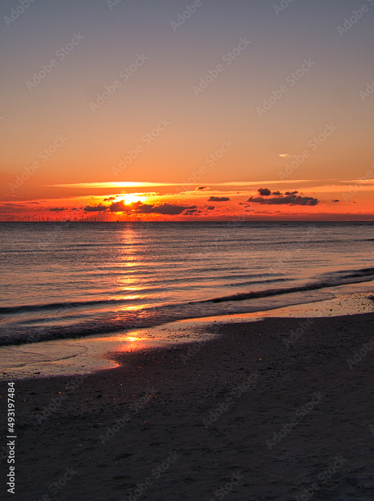 Sunset by the sea in colorful play of light in the clouds. Blåvand Denmark.