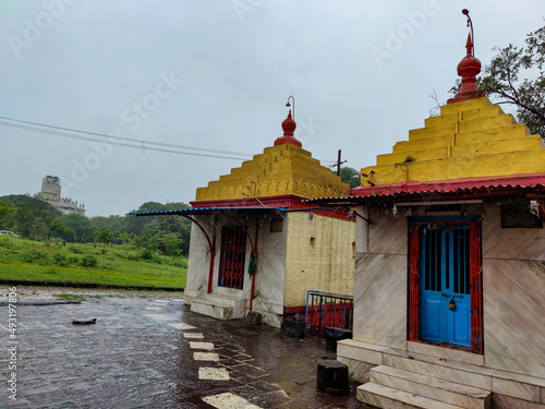 Stock photo of two ancient hindu temple of goddess Renuka devi, Temple building painted with light yellow color, roof painted with yellow color and red color peak.Picture captured during heavy raining photo