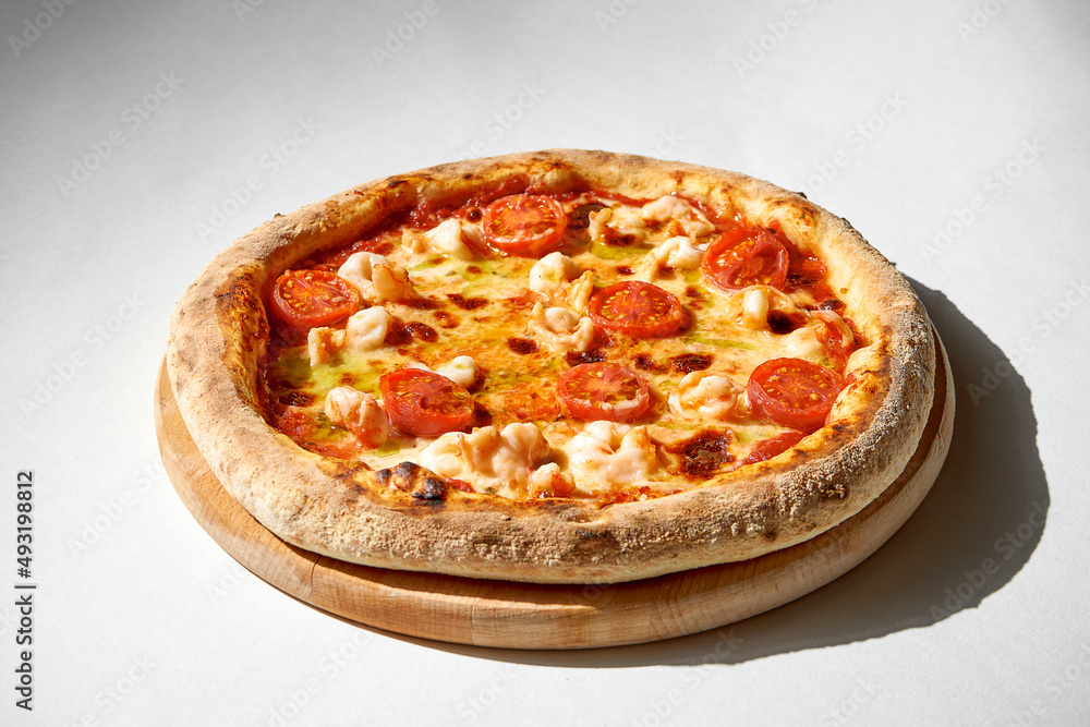Crispy chicken and tomato pizza on a gray background.