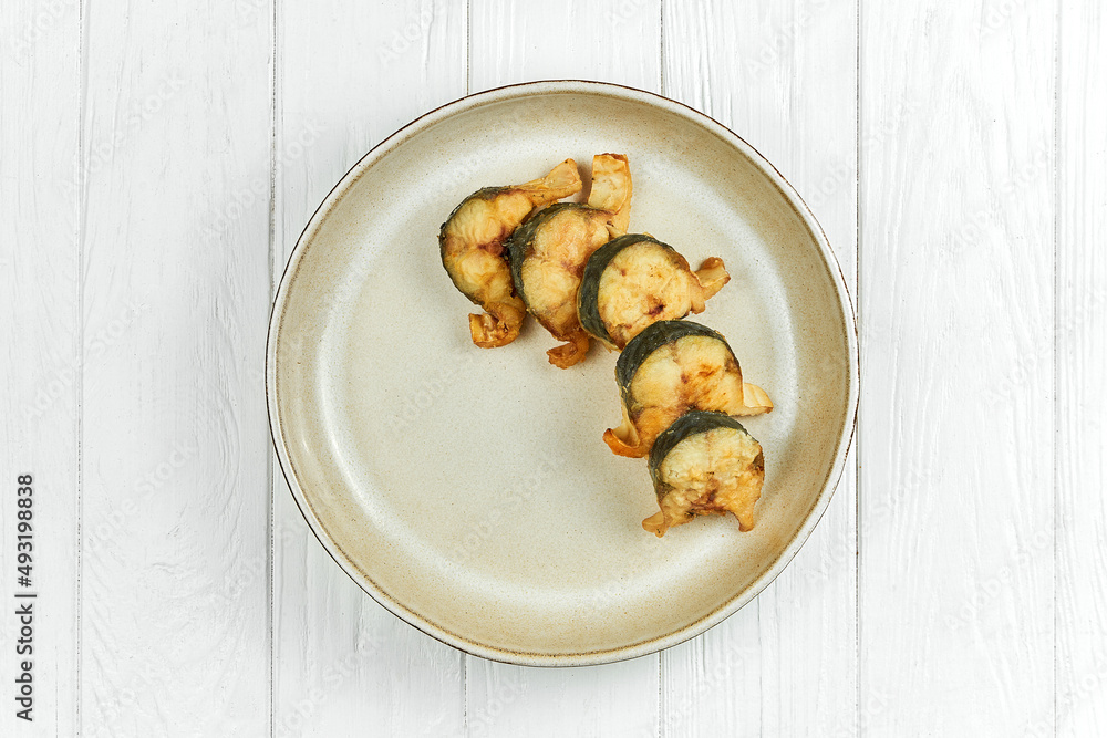 Fried mackerel in a plate on a white wooden background Fried mackerel in a plate on a white wooden background