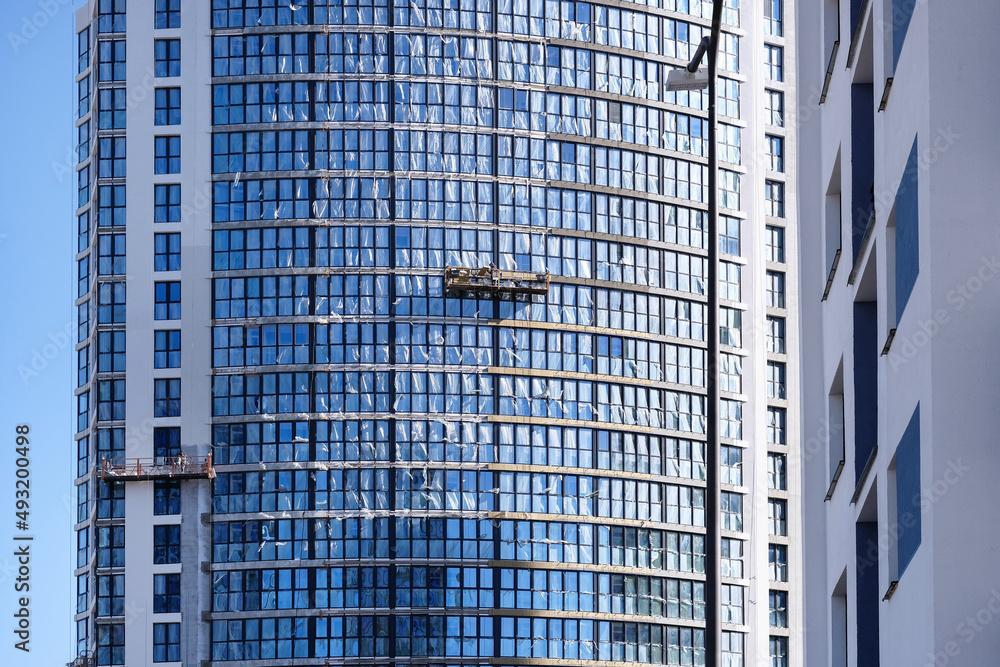 Construction of modern buildings. Workers install windows in cradles . High quality photo
