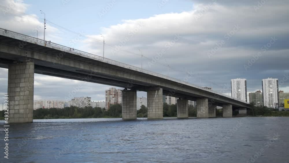 Point of view fast sailing on motorboat under the city bridge against the background of the coastline of the city with trees, shopping center and tall houses. Having fun driving speedboat on river Point of view fast sailing on motorboat under the city bridge against the background of the coastline of the city with trees, shopping center and tall houses. Having fun driving speedboat on river
