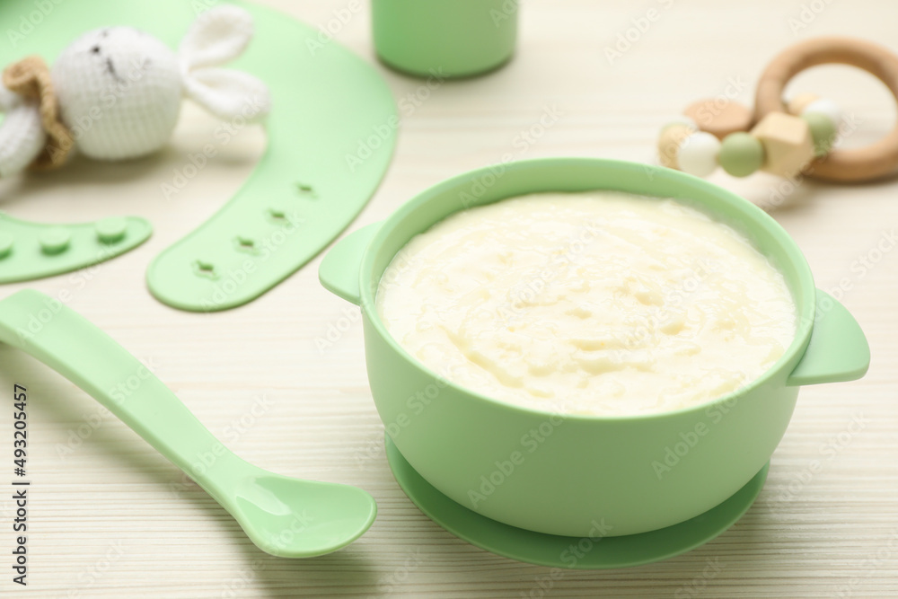 Plastic dishware with healthy baby food on white wooden table, closeup. Space for text Plastic dishware with healthy baby food on white wooden table, closeup. Space for text