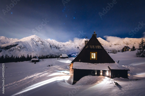 Fototapeta Naklejka Na Ścianę i Meble -  Mountain chalet in the Tatras during the blue hour. Winter mountain landscape with a view of the mountain ridges.