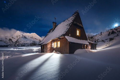 Fototapeta Naklejka Na Ścianę i Meble -  Mountain chalet in the Tatras during the blue hour. Winter mountain landscape with a view of the mountain ridges.