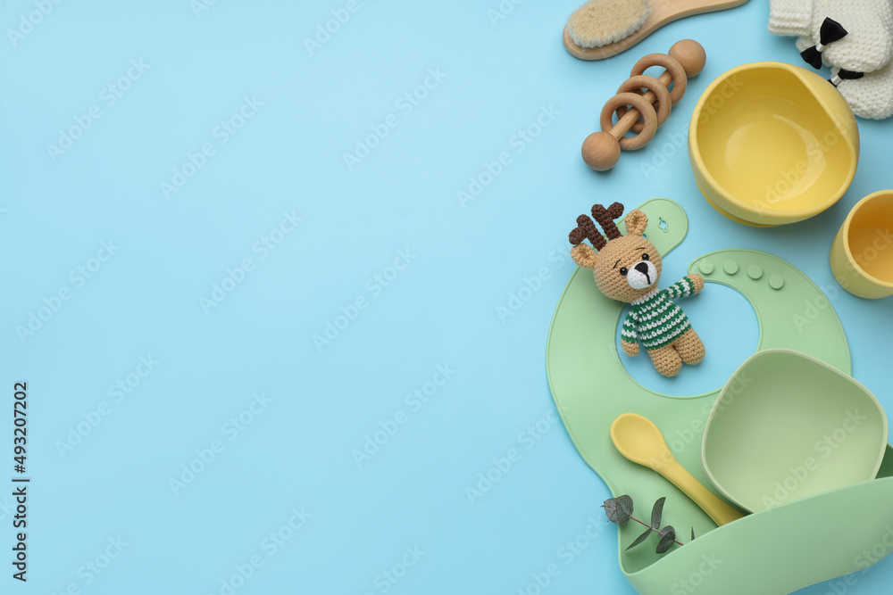 Naklejka premium Flat lay composition with baby feeding accessories and bib on light blue background, space for text