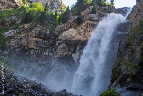 Beautiful waterfall in mountains with. Barskoon waterfall - splashes of Champaign. Travel  tourism in Kyrgyzstan concept.