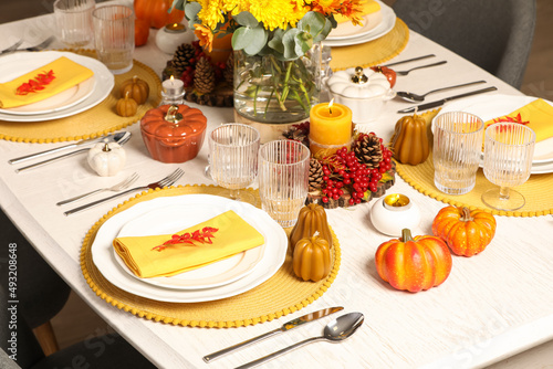 Autumn table setting with floral decor and pumpkins indoors