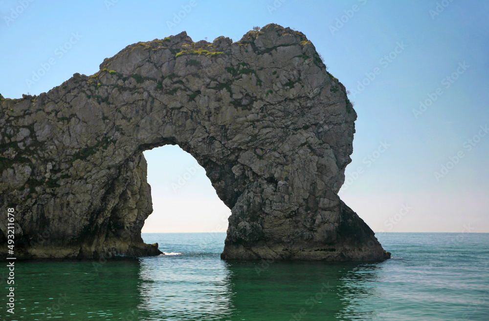 The famous rock formation known as Durdle Door from the beach, on a lovely sunny and calm day: Dorset, England, UK