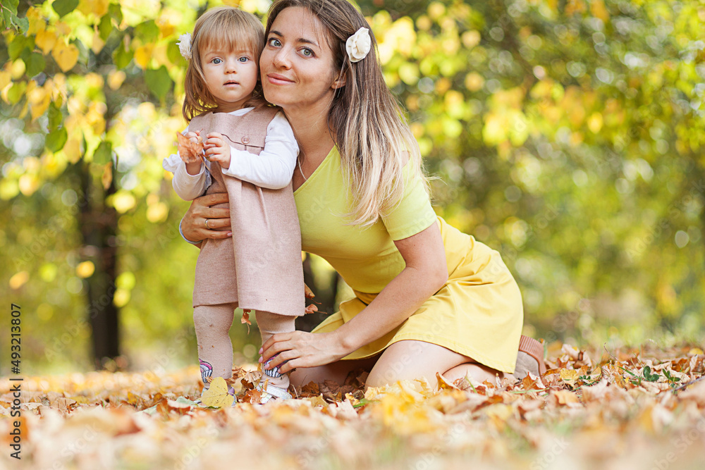 Beautiful young mother with her little daughter in park. Mother kissing her child outdoors. Family playing in autumn park. Beautiful young mother with her little daughter in park. Mother kissing her child outdoors. Family playing in autumn park.