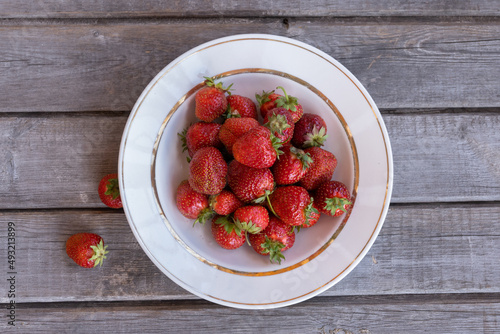 Ripe strawberries in a large white plate. Warm hot summer.