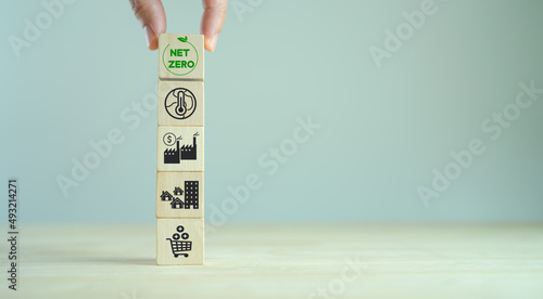Net zero target and carbon neutral. Green business concept. Climate changing problems solving goals..Stacking wooden cubes with net zero icon on pollution source icon on grey background and copy space