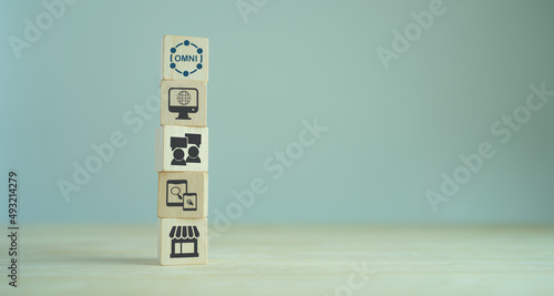 Omnichannel marketing concept. Digital online marketing commerce sale. Customer engagement integrated online and offline channels. Stacking wooden cubes with omni text standing on other omni icons. photo