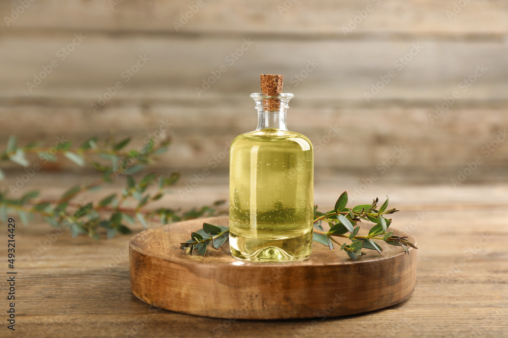 Bottle of eucalyptus essential oil and plant branches on wooden table Bottle of eucalyptus essential oil and plant branches on wooden table