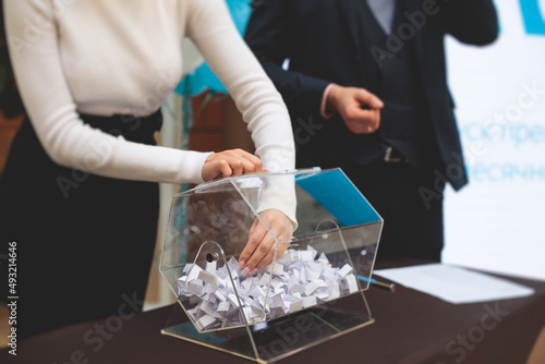 Process of prize drawings, extracting a winning numbers of lottery machine, raffle drum with bingo balls and winning tickets on event with a host and hands on lottery machine