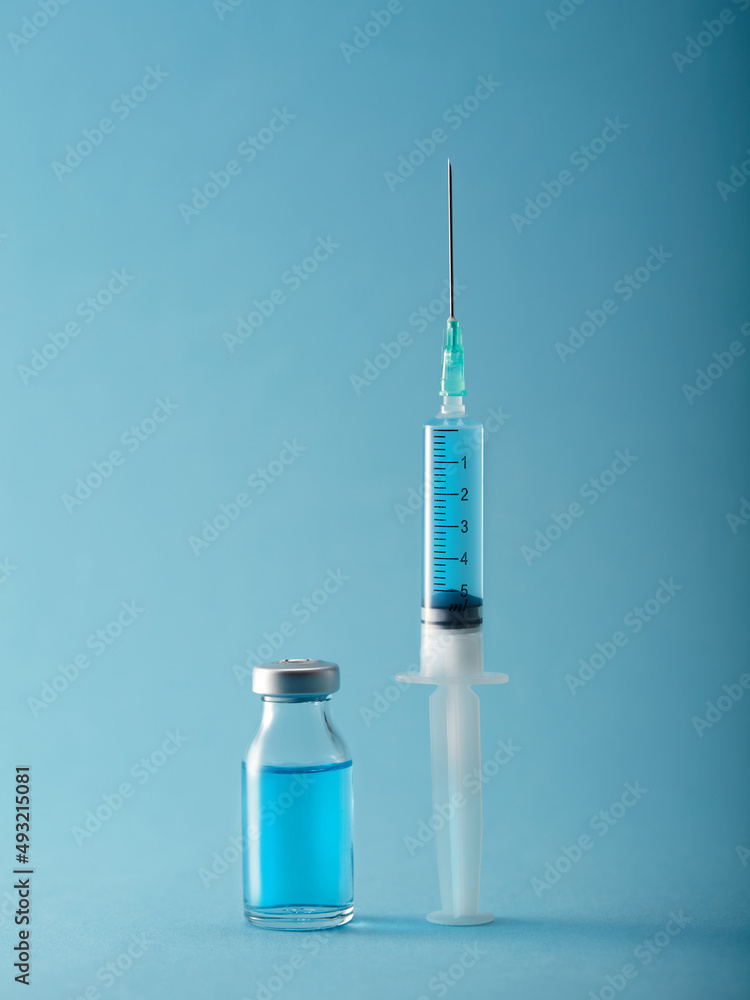 Vaccine and syringe injection on blue background. Vertical compozition Vaccine and syringe injection on blue background. Vertical compozition
