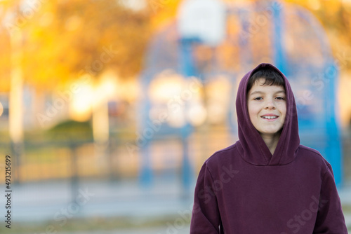 Smiling teen boy 14-16 year old wearing hoodie outdoors. Looking at camera. Teenager hood.