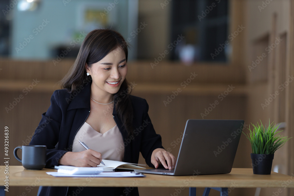 Attractive mature businesswoman working on laptop in her workstation. Smiling young Asian businesswoman working on a laptop at her desk in office. Attractive mature businesswoman working on laptop in her workstation. Smiling young Asian businesswoman working on a laptop at her desk in office.