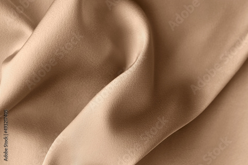 Luxury light brown beige color creased smooth satin silk cloth texture decorate background with minimalistic style and copy or negative space