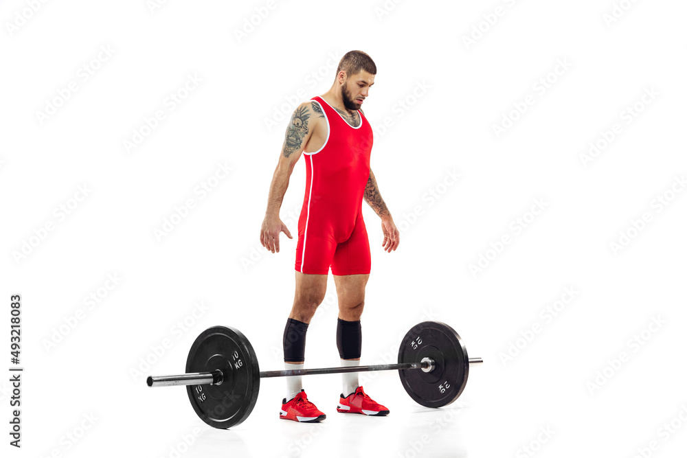 Full length portrait of man in red sportswear exercising with a weight isolated on white background. Sport, weightlifting, power, achievements concept Full length portrait of man in red sportswear exercising with a weight isolated on white background. Sport, weightlifting, power, achievements concept
