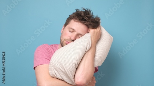 Caucasian man is tired and very sleepy keeping pillow on head.