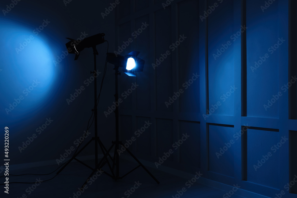 Bright blue spotlights near wall in dark room, space for text