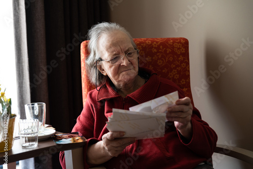 Pensionner lady looking at pictures in her couch at home