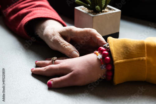 Close up of the wrinkled hands of a 83 year old white mother and her 39 year old daughter with the Down Syndrome