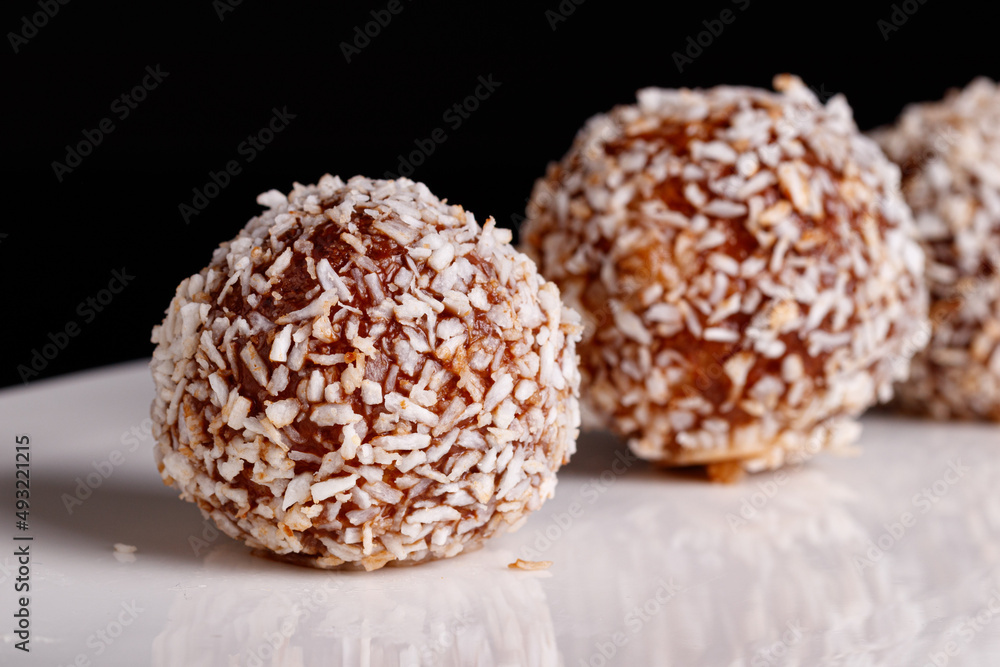 Beautiful sweets with coconut on a white plate on a black background Beautiful sweets with coconut on a white plate on a black background