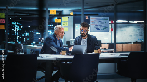 Businesspeople in Modern Office: Business Meeting of Two Managers. CEO and Operations Director Talk, Discuss, Brainstorm Corporate Strategy, Implementing Marketing and Financial Plans. Evening Time. photo
