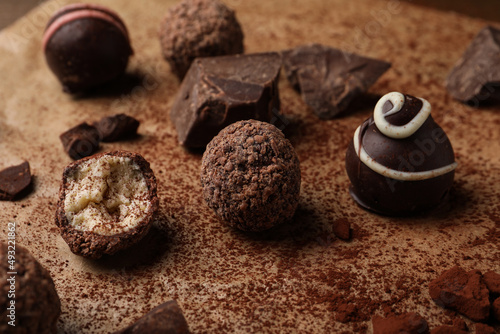 Different delicious chocolate truffles on parchment paper, closeup