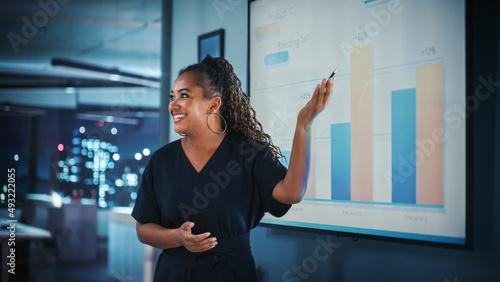 Company Operations Director Holds Sales Meeting Presentation for Employees and Executives. Creative Black Female Uses TV Screen with Growth Analysis, Charts, Ad Revenue. Work in Business Office.