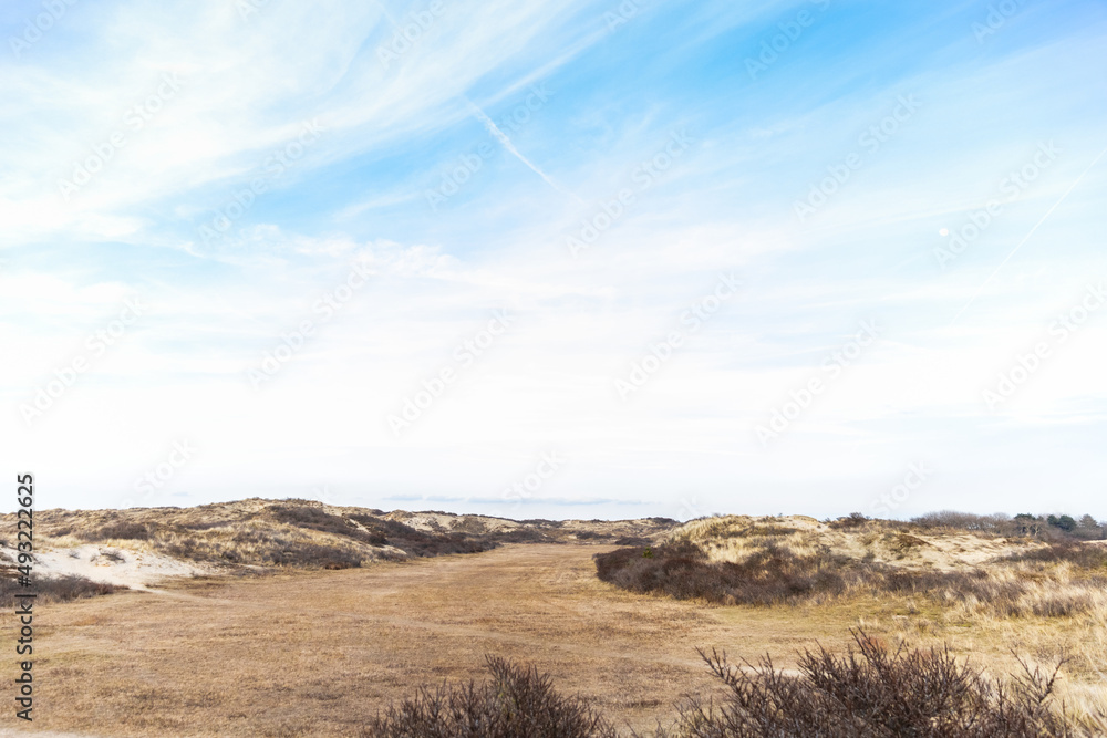 sand dunes with grass field in the middle and blue sky met a few clouds sand dunes with grass field in the middle and blue sky met a few clouds