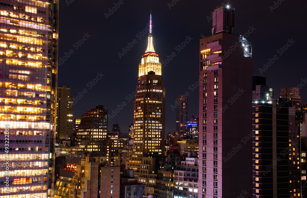 A shot of the Empire State Building Manhattan New York citiscape skyline at night. The shot was taken on 42nd St looking into the skyscrapers lit up with their internal lights