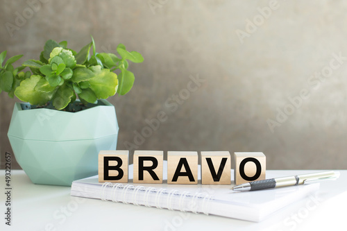 Word BRAVO on wooden cubes on an office desk, a business concept