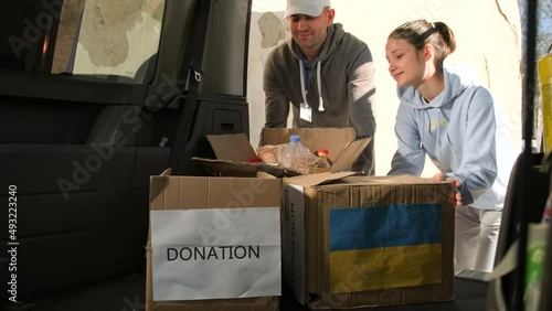 Volunteers putting the cardboard boxes with food and drink in the car trunk to deliver them to the ukranian refugees people. photo