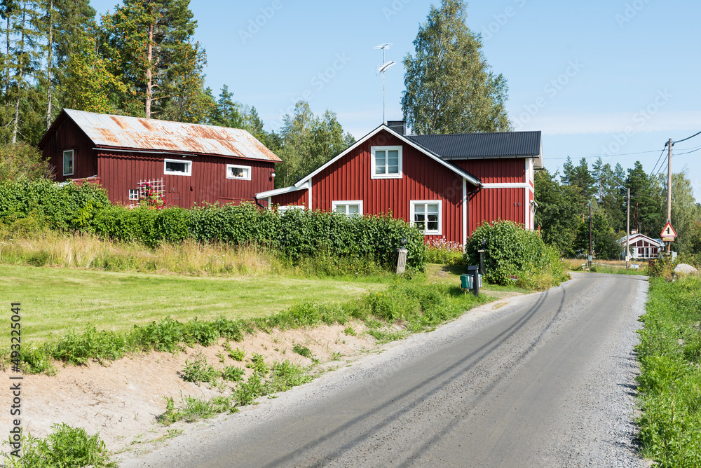 Borka, Gavleborgs Lan, Sweden - Countryroad towards the village with typical Swedish summerhouses in red wood Borka, Gavleborgs Lan, Sweden - Countryroad towards the village with typical Swedish summerhouses in red wood