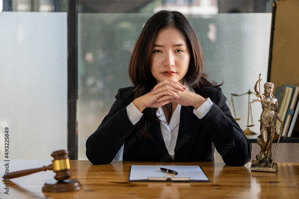 A female lawyer working with laptop, hammer in lawyer's office with the goddess of justice with scales, advice, and concepts of justice. A female lawyer working with laptop, hammer in lawyer's office with the goddess of justice with scales, advice, and concepts of justice.