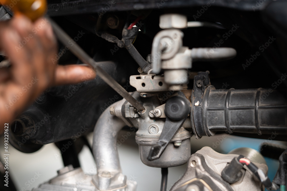 Fototapeta premium Close up shot of mechanic busy fixing motorbike air filter at garage - concept of repair and maintenance service.