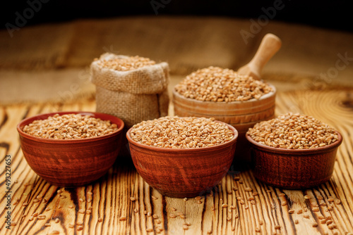 Billede på lærred Pearl barley groats in bowls and bags on a wooden background