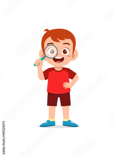 little boy standing and holding magnifying glass