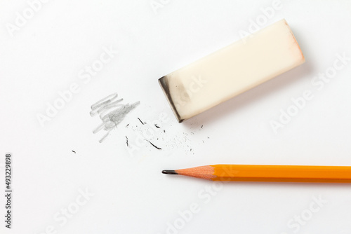 Eraser with traces of dust and a pencil on a white sheet