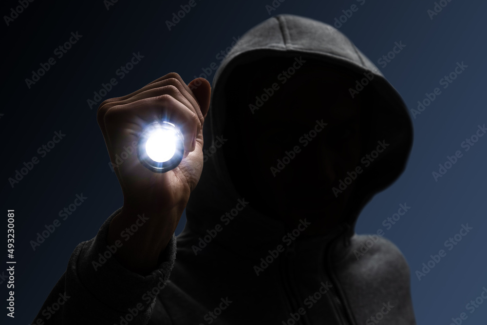 Hooded burglar. Silhouette of thief and flashlight - obrazy, fototapety, plakaty 